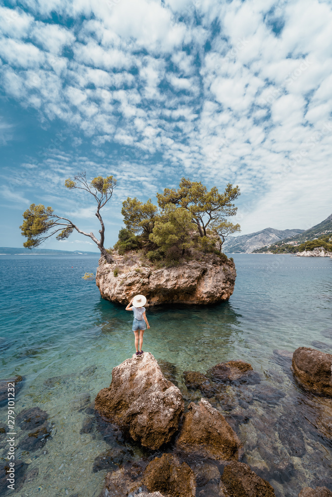 A girl with a straw hat in front of the island symbol of Brela in Dalmatia, Croatia