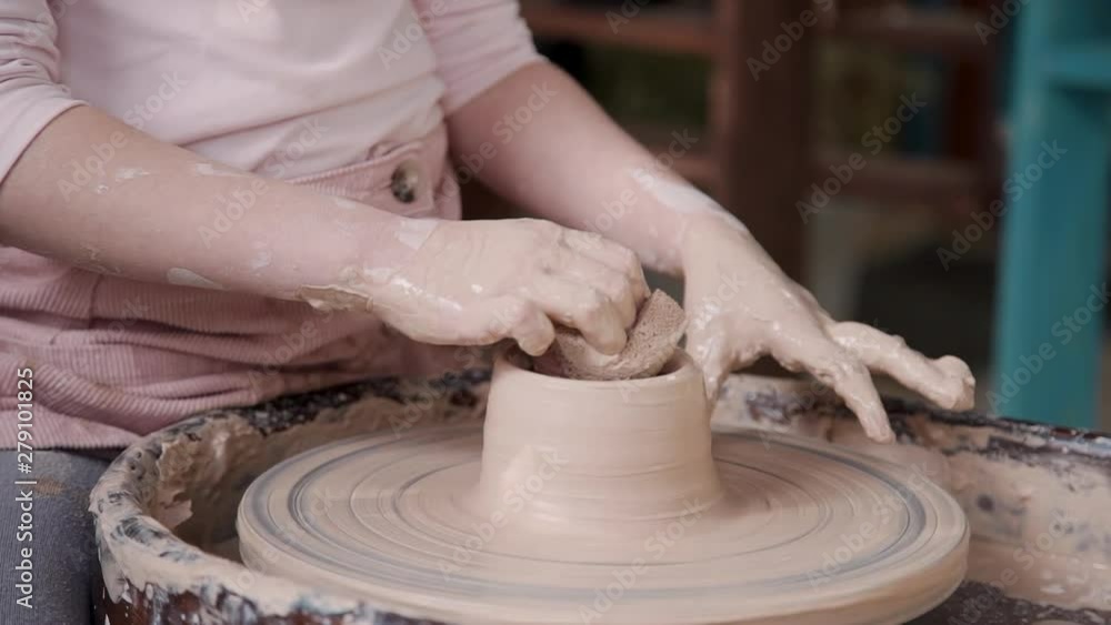 Small child girl molding wet clay and sitting on chair inside bright studio or work space with natural soft light. Careless and carefree kid using spining wheel and making craft object Small child girl molding wet clay and sitting on chair inside bright studio or work space with natural soft light. Careless and carefree kid using spining wheel and making craft object