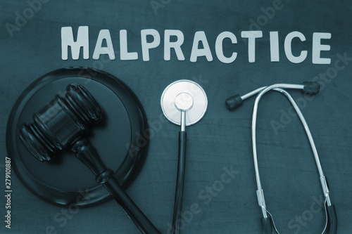 Wooden judge gavel and stethoscope on table, malpractice concept photo