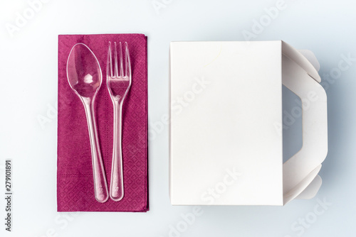 White Cardboard Fast Food Box  Packaging For Lunch and plastic fork and spoon on purple serviette. On White Background Isolated. Ready For Your business design