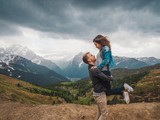 Brunette girl hugging a boy, walking on the lawns in the mountains.