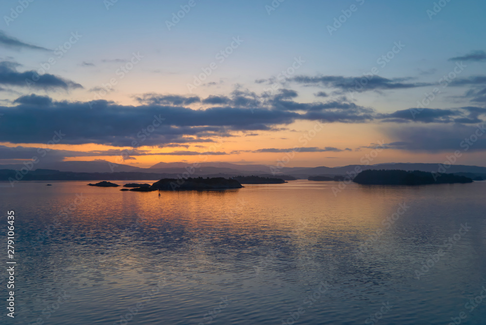 Dawn beginning to break over Islands in the Bergen Fjord on a calm winters morning, with ripples playing across the water surface. Norway.