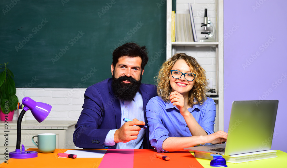 Smiling teachers couple in classroom. University students at college. Girl student with bearded teacher in auditorium. Learning, education concept. Funny young teacher with young student in classroom. Smiling teachers couple in classroom. University students at college. Girl student with bearded teacher in auditorium. Learning, education concept. Funny young teacher with young student in classroom.
