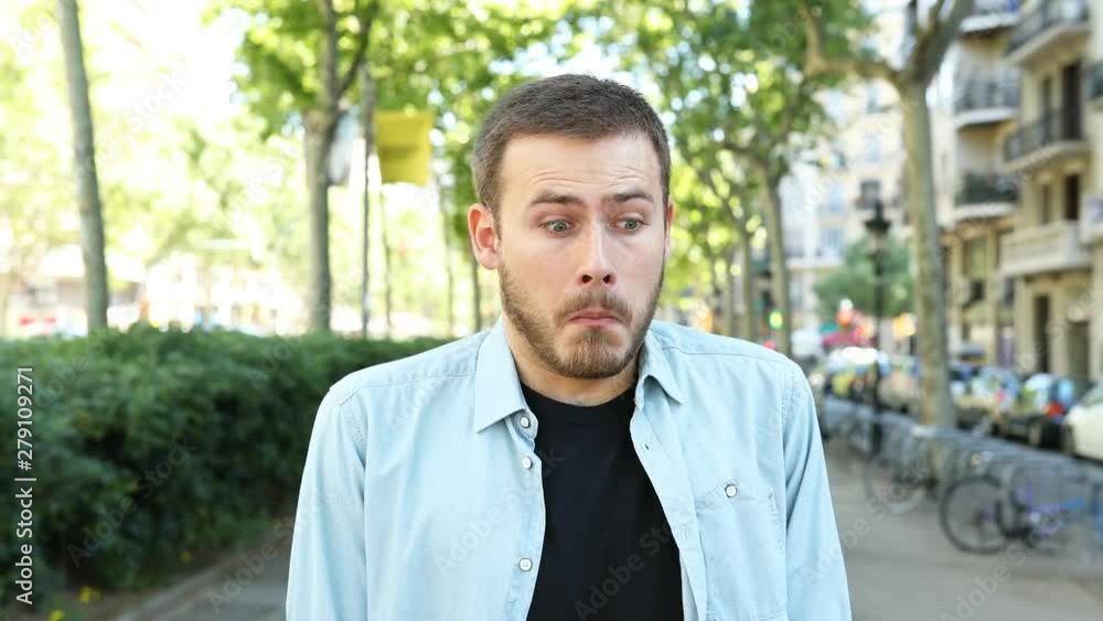 Front view portrait of a perplexed man looking at camera in the street Front view portrait of a perplexed man looking at camera in the street