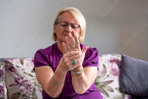 Elderly woman suffering from pain in hand, arthritis old person and senior woman female suffering from pain at home photo