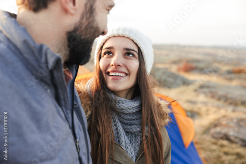 Happy young loving couple outside with tent in free alternative vacation camping over mountains.
