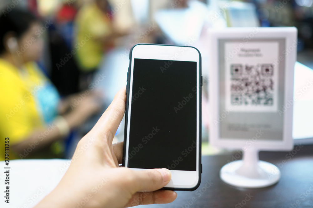 Hands use the phone to scan the QR code to accumulate points before paying at the counter.
