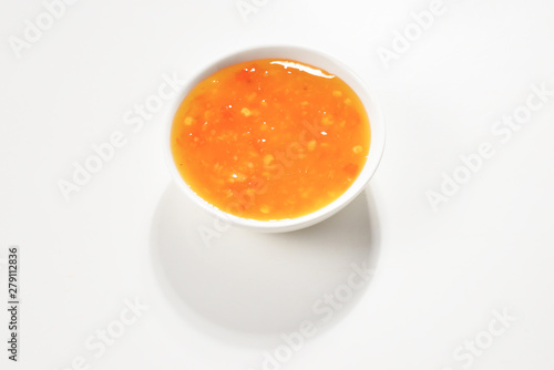 Orange sauce in white plate on white background.