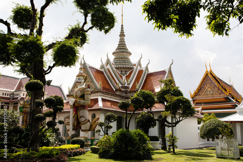 Fototapeta premium View of the roof of a Buddhist temple in Bangkok with white sky and green leaves