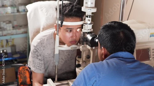An adult is having an eye disease and a doctor is checking him up in his medical room photo