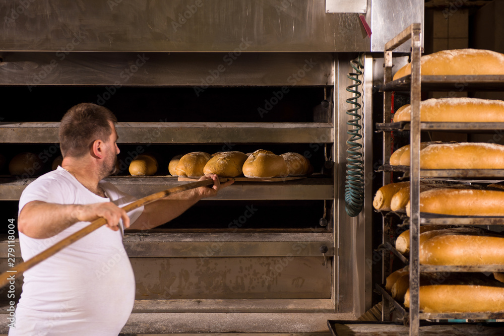 bakery worker taking out freshly baked breads