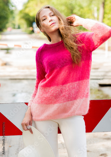 The beautiful woman model poses in a beautiful knitted pullover in the park on the road