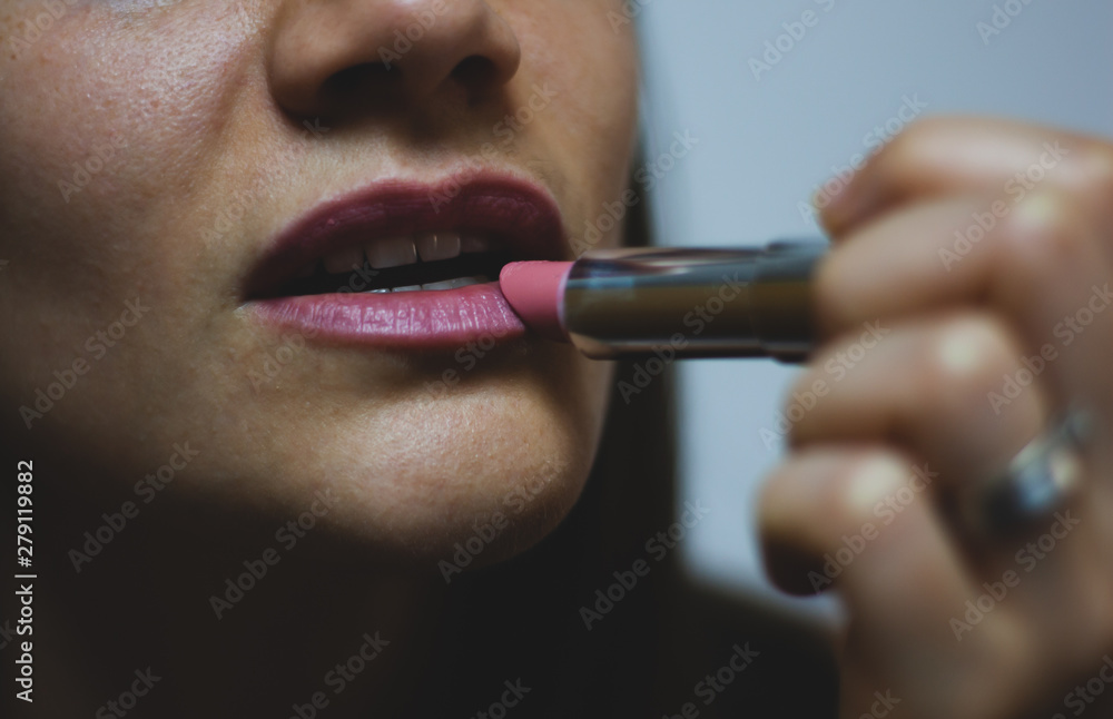 Girl applying lipstick in the mirror