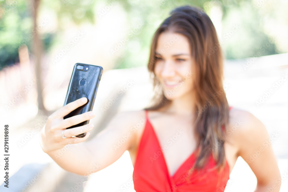 Beautiful girl in red dress taking selfie with smartphone Beautiful girl in red dress taking selfie with smartphone