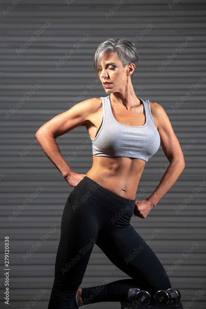 Woman Poses in Gym with dumbells. 
