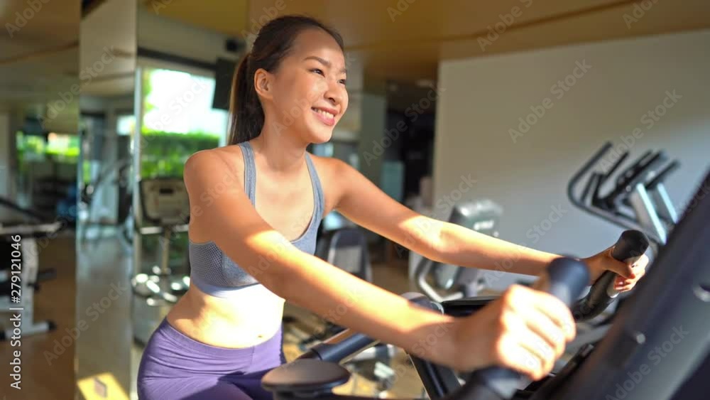 Close up beautiful Asian girl doing sport biking in the gym for fitness Close up beautiful Asian girl doing sport biking in the gym for fitness