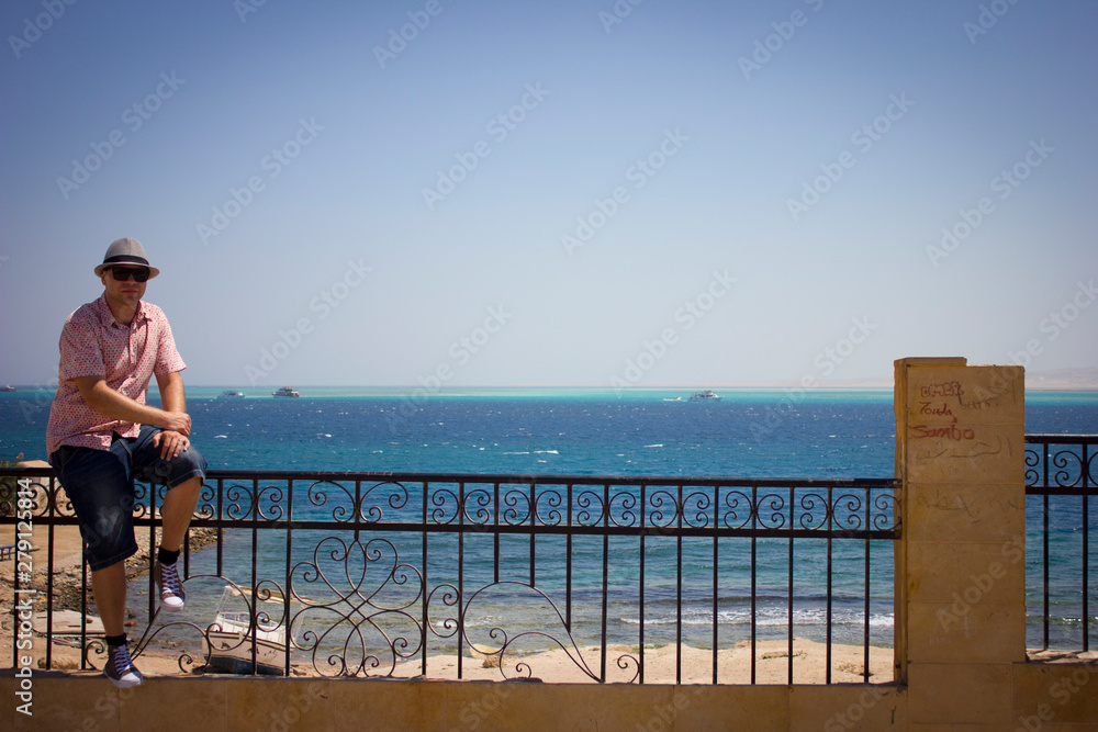 man sitting on pier and looking at the sea