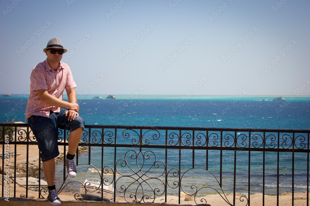man sitting on bench and looking at the sea