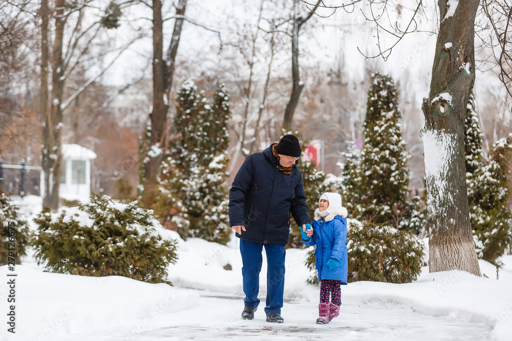 Grandfather carries granddaughter through the snow, grandfather and granddaughter spend time in winter