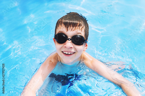 happy baby in the pool. boy swims in the pool with swimming glasses. . boy learning to swim © stopabox
