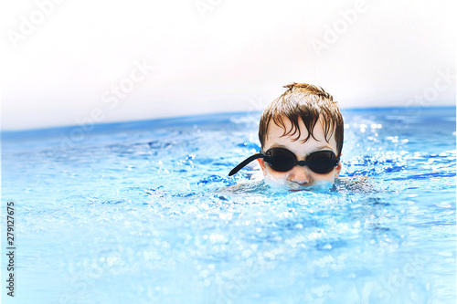 boy dives in swimming pool with swimming glasses. boy swims in the pool. child learning to swim