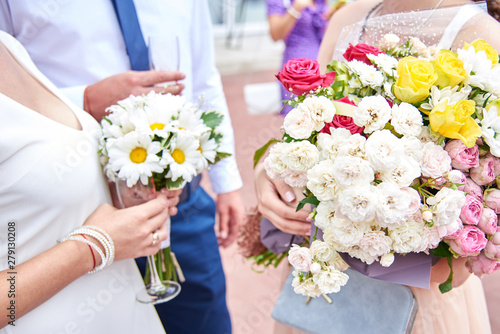 Bride and groom hold glasses of champagne and a bouquet on their wedding day