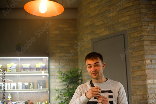 Vape man. Indoor portrait of a young handsome white caucasian guy in vape bar. Bad habit. Close up.