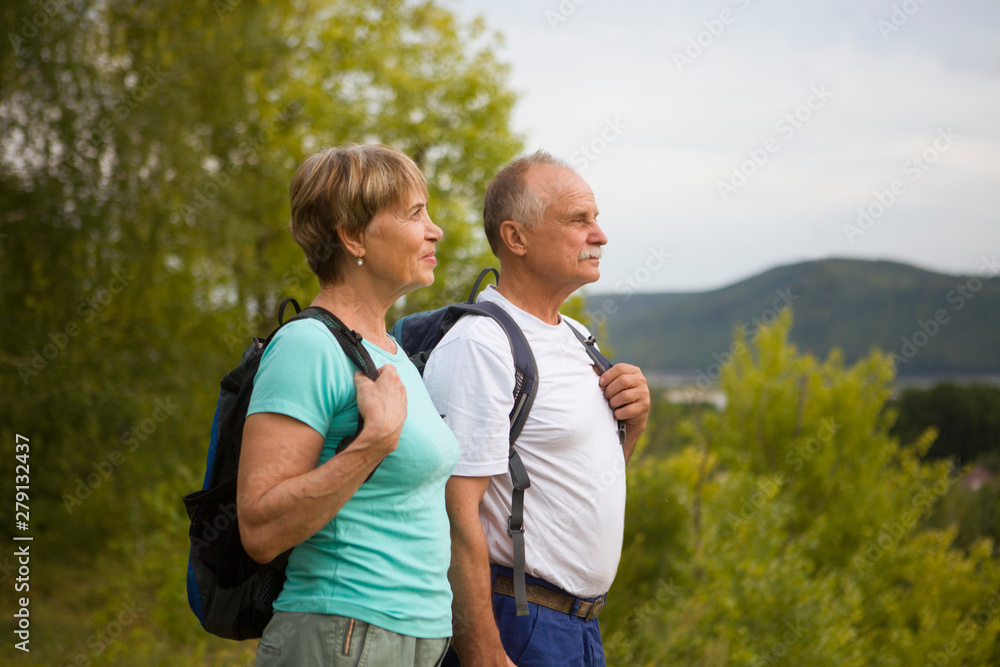 elderly couple with backpack  on the mountain. Senior couple walking in nature. travel tourism concept