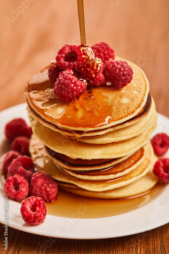 close up view of plate with pancakes and raspberries with syrup