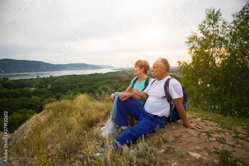 elderly couple with backpacks sits on the mountain. Senior couple walking in nature. travel tourism concept