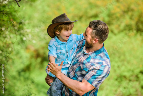 Rustic family. Growing cute cowboy. Small helper in garden. Little boy and father in nature background. Spirit of adventures. Strong like father. Child having fun cowboy dad. Power being father © be free
