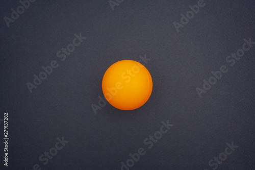Orange ping pong ball on a black background in the center. Top view © droidfoto