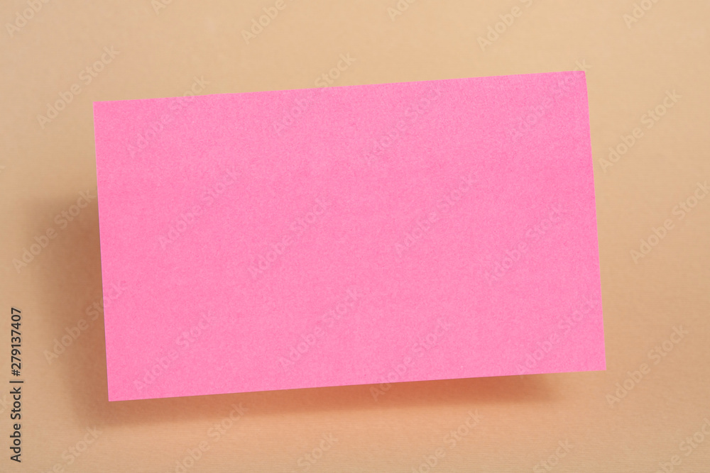 Pink paper sticker for text hanging in the air on a beige background. Blank or template. Pink paper sticker for text hanging in the air on a beige background. Blank or template.