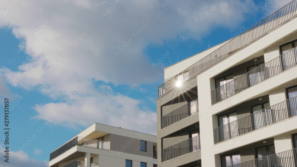White clouds floating in the blue sky over a block of flats.