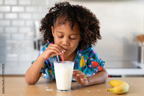 Young girl blowing bubbles in a glass of milk