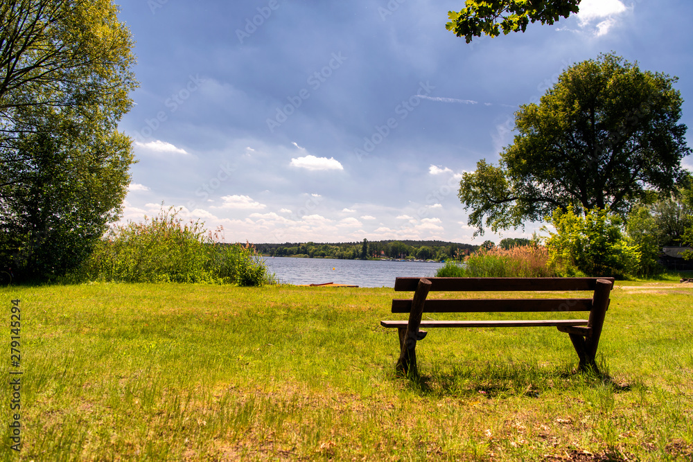 simple wooden bench on a lake shore simple wooden bench on a lake shore
