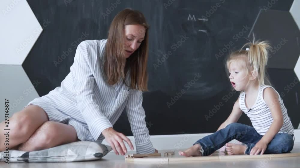 Mom and her little daughter are building a railroad at home. Family day off, morning with baby Mom and her little daughter are building a railroad at home. Family day off, morning with baby
