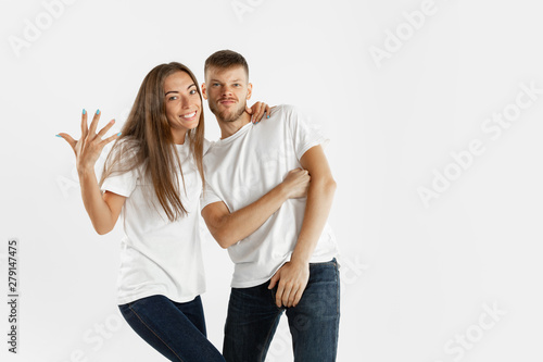 Beautiful young couple's portrait isolated on white studio background. Facial expression, human emotions, advertising concept. Copyspace. Woman and man standing crossing hands or dancing, look cool.