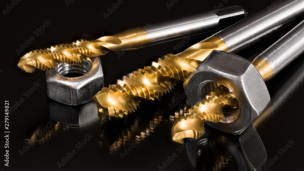 Titanium coated spiral flute taps and threaded nuts on black background. Artistic still life of sharp steel cutting tools for hand-tapping with reflection on shiny surface. Chip machining, metal work. Titanium coated spiral flute taps and threaded nuts on black background. Artistic still life of sharp steel cutting tools for hand-tapping with reflection on shiny surface. Chip machining, metal work.