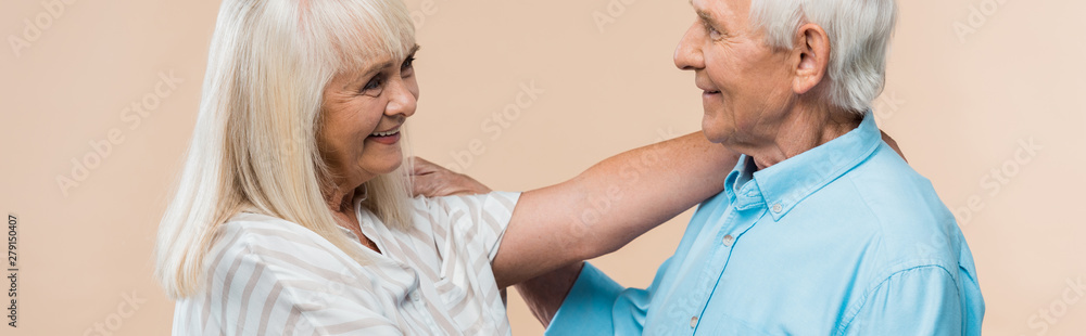 panoramic shot of senior woman smiling while looking at pensioner isolated on beige panoramic shot of senior woman smiling while looking at pensioner isolated on beige