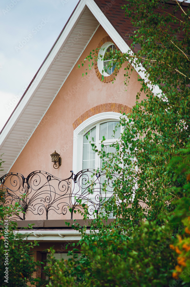 Obraz premium Fragment of a beautiful country house, close-up. Roof, window and balcony with a wrought-iron lattice.