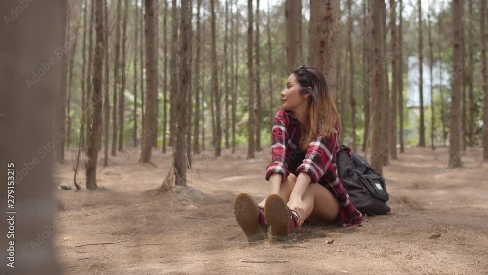 Asian hiker woman trekking in forest. Young happy backpack girl sitting rest tired after walking travel nature and adventure trip, climb mountain in summer holidays vacation concept. Slow motion. Asian hiker woman trekking in forest. Young happy backpack girl sitting rest tired after walking travel nature and adventure trip, climb mountain in summer holidays vacation concept. Slow motion.
