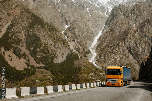 Big yellow truck rides on the road in the mountains photo