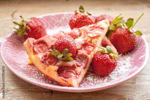 Piece of round strawberry berries tart pie pudding on pink plate on rustic wooden background
