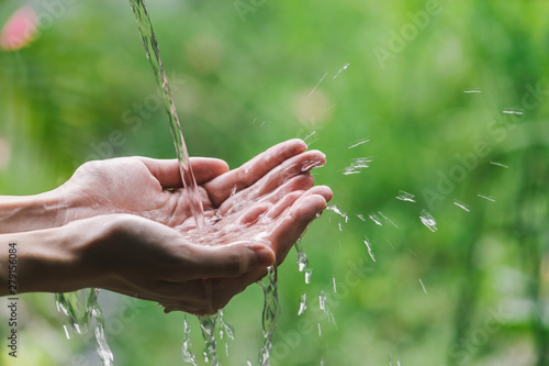 Closeup water flow to hand of women for nature concept on the garden background.