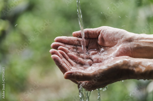 Closeup water flow to hand of women for nature concept on the garden background.