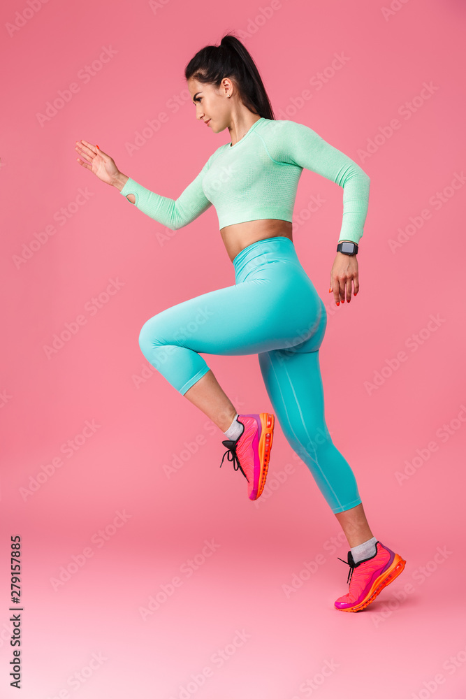 Serious young sports fitness woman isolated over pink wall background running. - obrazy, fototapety, plakaty 