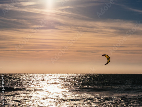Lone kite surfer surfing at sunset
