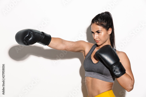 Gorgeous young sports fitness woman boxer isolated over white wall background make boxing exercises with gloves. © Drobot Dean