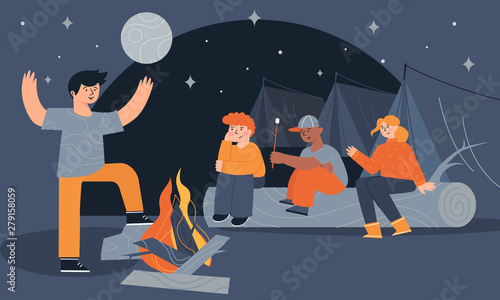 Children sitting near a campfire and tents eating marshmallow and telling scary stories at night. Camping trip, backpacking, and traditional bonfires in scout camp. Kids summer camp outdoor activity.